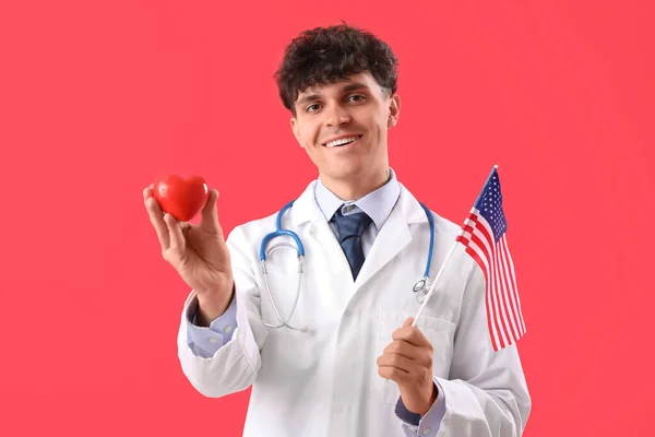 Kırmızı Arka Planda Amerikan Bayrağı Kalbi Olan Bir Erkek Doktor — Stok fotoğraf