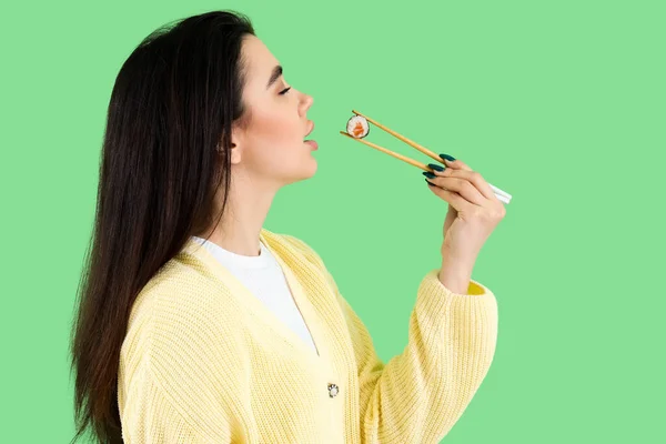 Ung Kvinna Äter Sushi Rulle Grön Bakgrund — Stockfoto