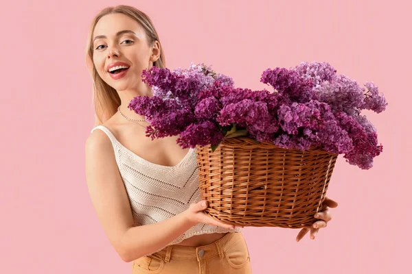 Junge Frau Mit Korb Mit Lila Blumen Auf Rosa Hintergrund — Stockfoto