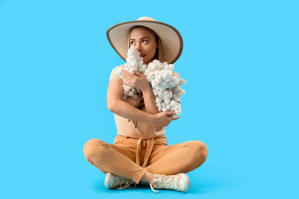 Ung Kvinna Med Lila Blommor Sitter Blå Bakgrund — Stockfoto