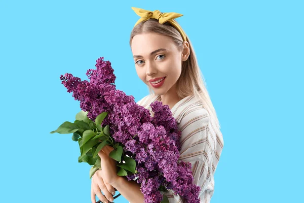 青の背景にライラックの花を持つ若い女性 — ストック写真