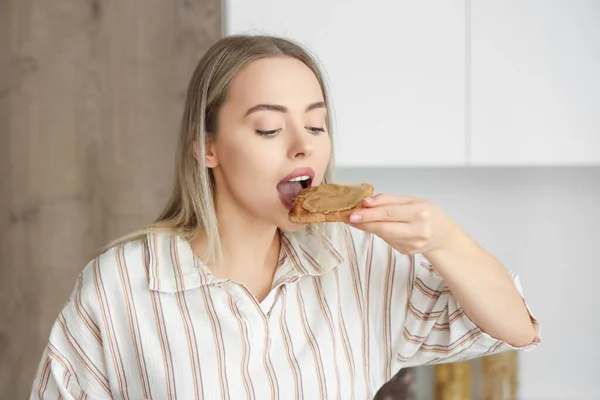Νεαρή Γυναίκα Τρώει Τοστ Βούτυρο Καρύδας Στην Κουζίνα Κοντινό Πλάνο — Φωτογραφία Αρχείου