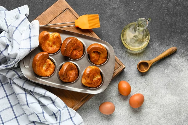 Baking tin with tasty Yorkshire pudding and ingredients on grunge background
