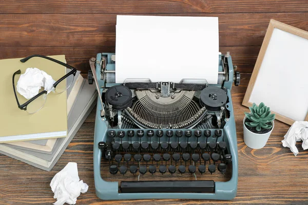 stock image Vintage typewriter with books, empty frame and eyeglasses on brown wooden background