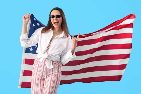 青い背景に 悪魔の角 を示す米国の旗を持つ若い女性 — ストック写真