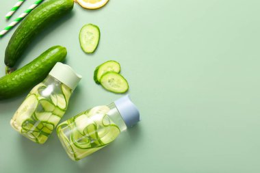 Yeşil arka planda salatalık dilimli spor şişeleri.