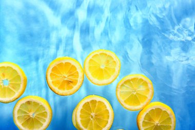 Mavi arka planda suda taze limon dilimleri
