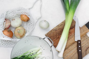 Tahta ve kevgir. Beyaz arka planda farklı soğan çeşitleri var.