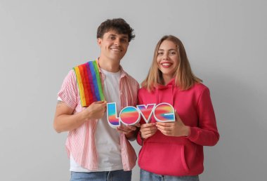 LGBT bayrağı taşıyan genç bir çift ve arka planda kelime aşkı