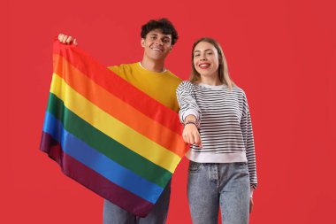 Kırmızı arka planda LGBT bayrağı olan genç çift