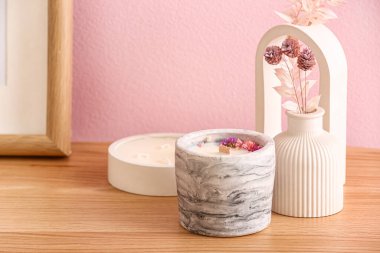 Odadaki pembe duvarın yanında elinde mumlar ve dekor olan tutucular, yakın plan.