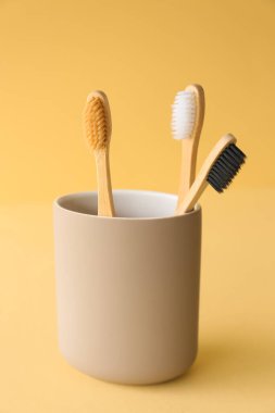 Bambu diş fırçaları bej arka planda tutucuda
