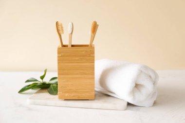 Bambu diş fırçaları tutacakta, havlu da arka planda.