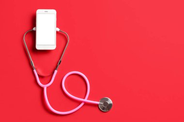 Kırmızı arkaplanda steteskop ve cep telefonu