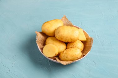 Mavi arka planda çiğ bebek patatesli kase