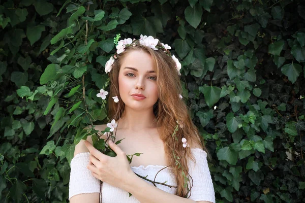 Vacker Ung Kvinna Med Blommor Håret Nära Grön Murgröna Utomhus — Stockfoto