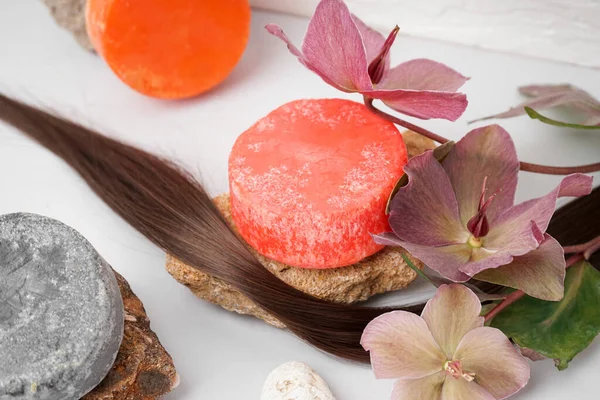 Solid shampoo bars with stones, hair and flowers on table
