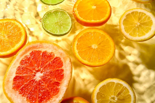 Různé Plátky Citrusových Plodů Vodě Žlutém Pozadí — Stock fotografie