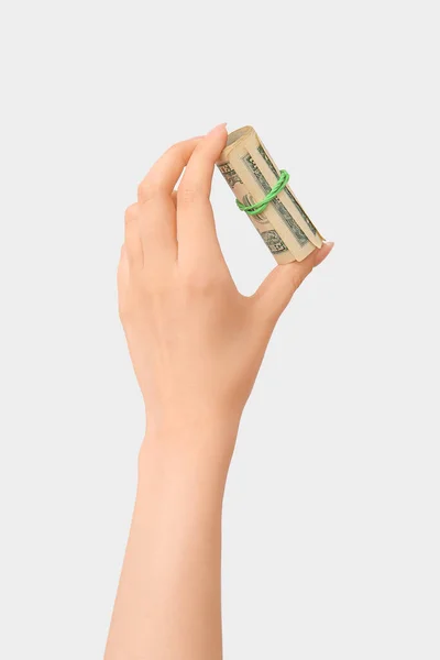 白い背景にゴムバンドで結ばれた100ドル紙幣のロールを持つ女性の手 — ストック写真
