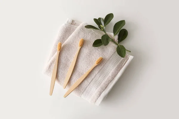 stock image Bamboo tooth brushes and towel on light background, top view