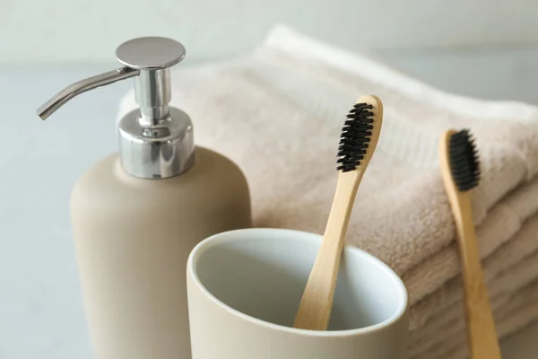 Bamboo tooth brushes, liquid soap and towels on grey background, closeup