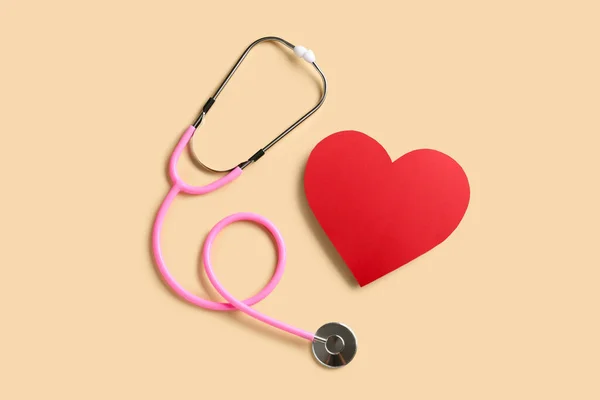 ベージュ地に聴診器と赤いハート 心臓病の概念 — ストック写真