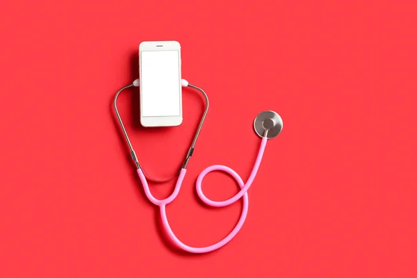 stock image Stethoscope and mobile phone on red background