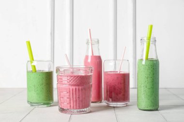 Bardaklar ve renkli içecekler beyaz masada.