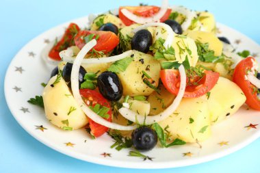 Mavi arka planda sebzeli lezzetli patates salatası, yakın plan.