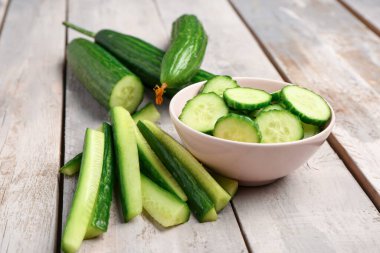 Hafif ahşap arka planda taze kesilmiş salatalık kasesi.