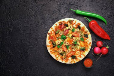 Sebzeli pizza, koyu arkaplanda malzemeler var.