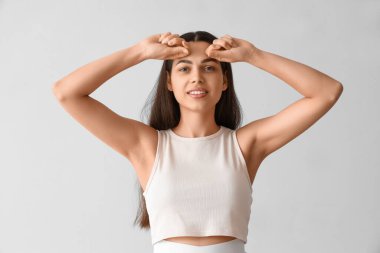 Genç kadın arka planda yüz geliştirme egzersizi yapıyor.