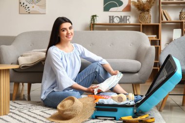 Genç bir kadın bavulunu bavula dolduruyor.