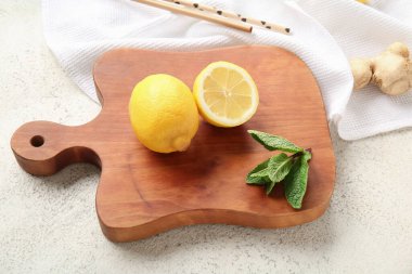 Limonlu ahşap tahta, grunge beyaz arka planda zencefil ve nane.