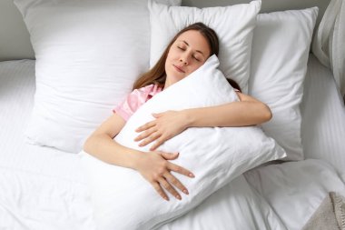 Güzel genç bir bayanın yumuşak yatakta uyuduğu bir sabah.