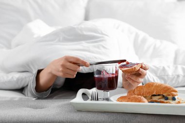 Genç bir kadının kahvaltısını yatak odasında yaptığı sabah, yakın plan.