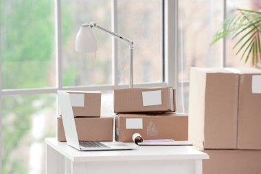 Ofiste dizüstü bilgisayarı, defteri ve paketleri olan işyeri