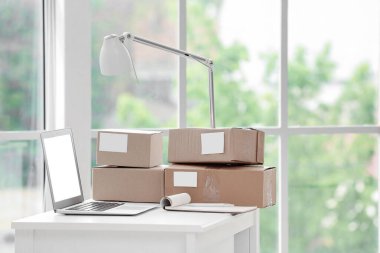 Ofiste dizüstü bilgisayarı, defteri ve paketleri olan işyeri