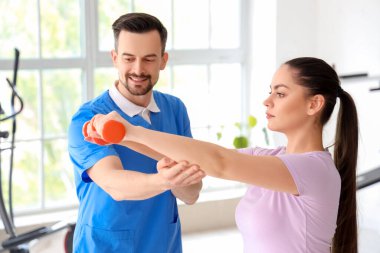 Genç bir kadınla rehabilitasyon merkezinde çalışan erkek fizyoterapist.