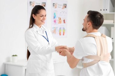 Sırt desteği ve rehabilitasyon merkezinde kadın fizyoterapisti olan genç bir adam.