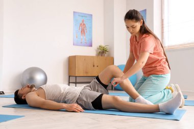 Rehabilitasyon merkezinde genç bir adamla çalışan kadın fizyoterapist.