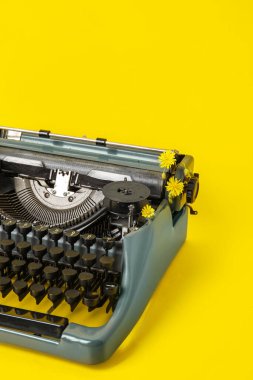 Sarı arka planda karahindiba çiçekli klasik daktilo