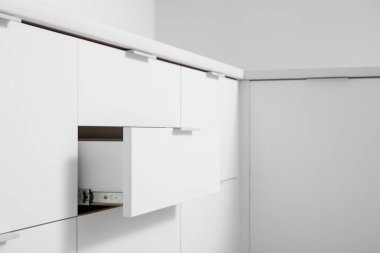 Açık mutfakta çekmeceleri olan beyaz tezgâhlar.