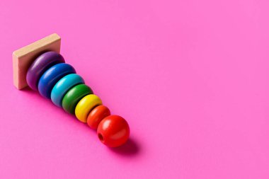 Pembe arka planda tahta renkli oyuncak piramidi. Çocuk Bayramı kutlaması
