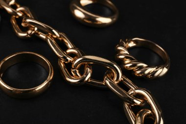 Güzel zincir bilezik ve siyah zemin üzerinde yüzükler