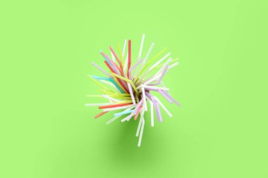 Yeşil zemin üzerinde farklı renkli pipetlerle kağıt bardak