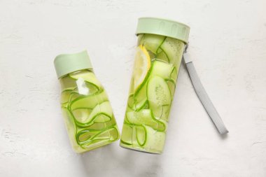 Beyaz masada salatalık dilimli spor şişeleri.