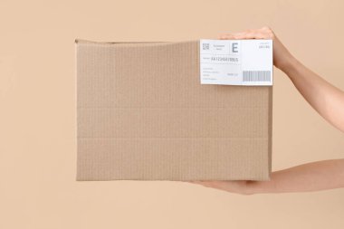 Hands of courier with parcel on beige background clipart