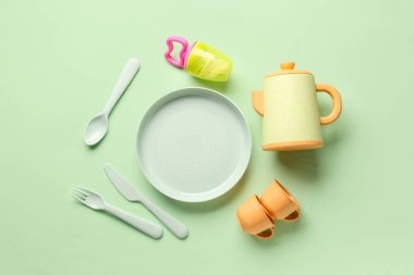 Soluk yeşil arka planda bebek için farklı yeme aletleri