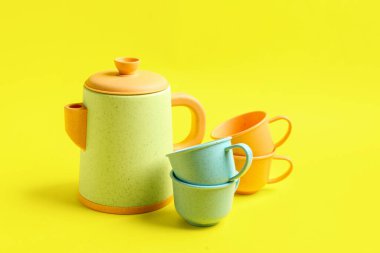 Sarı arka planda bebek için fincanları olan çaydanlık